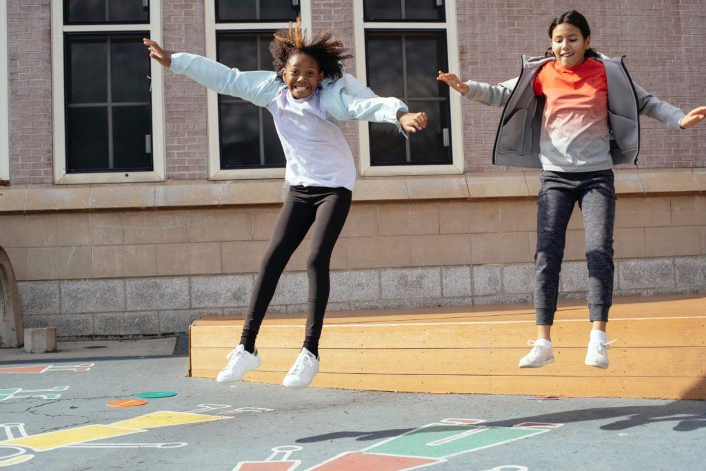 Two girls jumping on playground outside