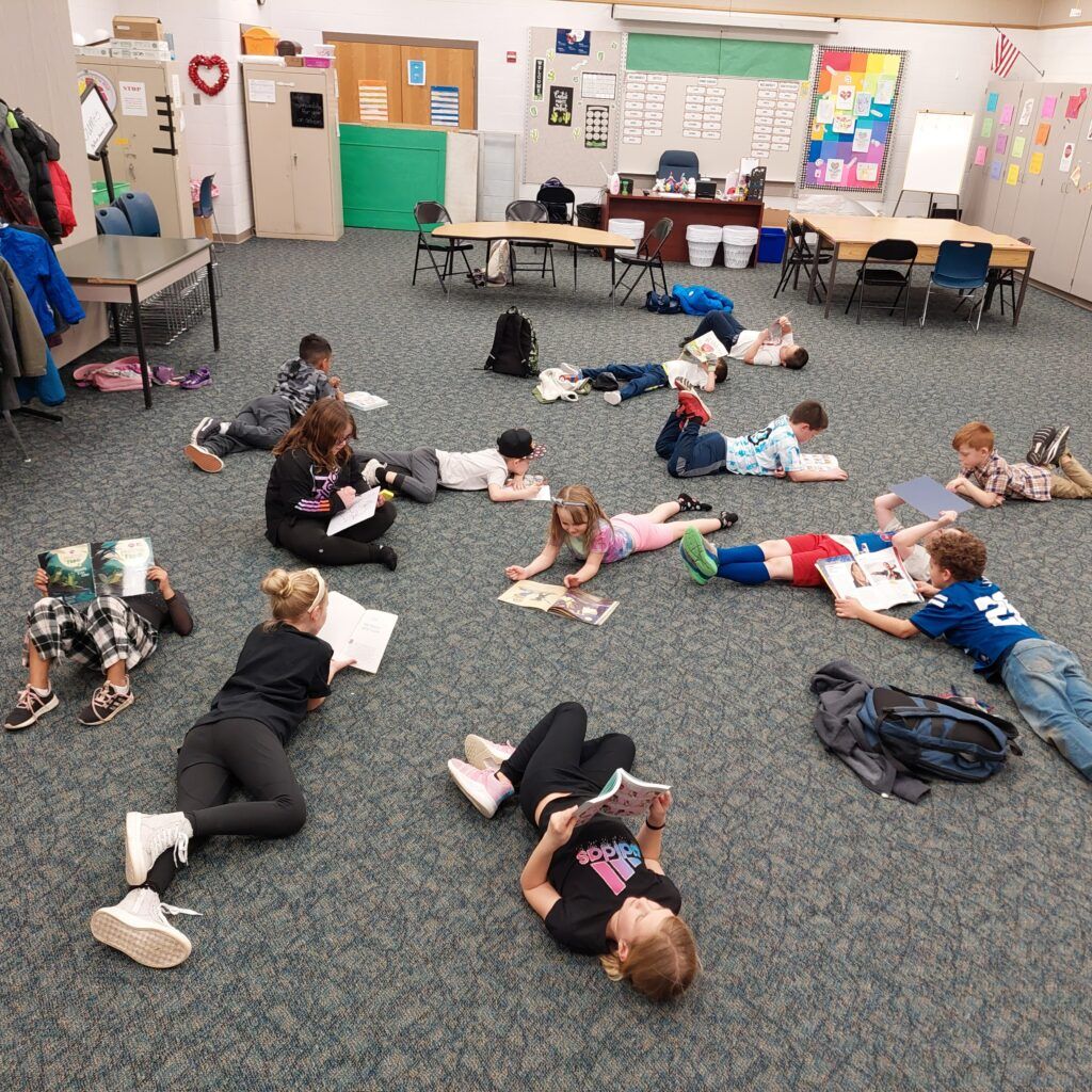Kids scattered on classroom floor reading in AYS before and after school program