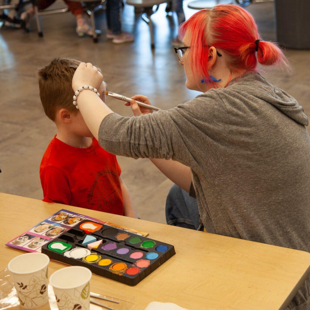AYS staff member painting boy's face in AYS before and after school program